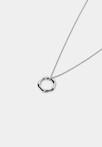 Collana d'argento con un pendente intrecciato e di forma organica appeso a una sottile catena. Il pendente ha una superficie liscia e riflettente.