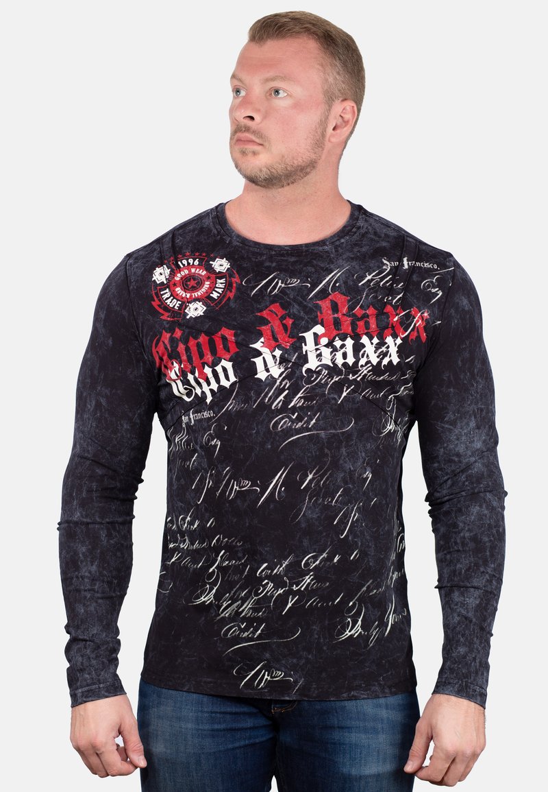 Langärmliges schwarzes Shirt mit texturiertem Finish, featuring roten und weißen Grafikdesigns, Schriftmustern und Markenlogo auf der Brust.