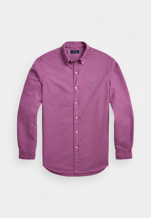 Camisa de manga larga abotonada en algodón de color púrpura claro, con cuello puntiagudo, bordado sutil del logo y puños abotonados.