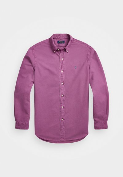 Srajca z dolgimi rokavi iz svetlo vijolične bombažne tkanine, z usnjenim ovratnikom, diskretno vezenim logotipom in gumbnimi manšetami.
