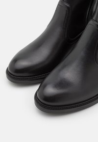 Czarne skórzane botki za kostkę o gładkiej fakturze, spiczastym nosku, elastycznych bocznych panelach oraz przeszyciu wzdłuż podeszwy. Prosty i klasyczny design.