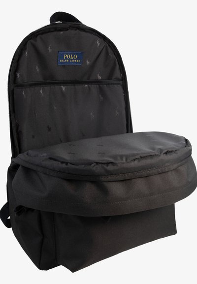 Čierny batoh so zatepleným vrchným klopom, textilnou nášivkou s logom a jemnou textúrou s malými vzorovými detailmi v interiéri.