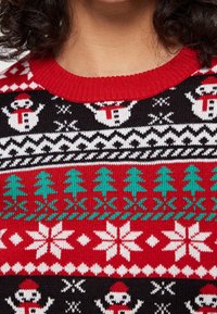 Maglione lavorato a maglia con una base nera e motivi rossi, verdi e bianchi, tra cui pupazzi di neve, alberi di Natale e fiocchi di neve; design con scollo rotondo.