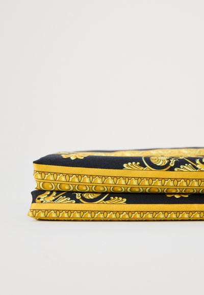 Złożona tkanina na czarnym tle z misternymi żółtymi wzorami kwiatowymi i geometrycznymi oraz fakturowaną ramką.