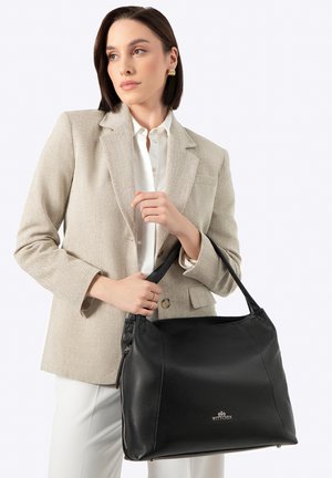 Zwarte leren handtas met een gestructureerd oppervlak, dubbele handvatten en ritssluiting. Voorzien van een logo aan de voorkant en een minimalistisch ontwerp.