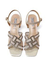 Sandali in pelle beige con cinturino alla caviglia, punta quadrata e design decorativo incrociato. Presentano dettagli metallici e una finitura testurizzata.