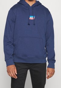 Felpa con cappuccio blu navy in misto cotone, con tasca frontale e logo Levi's colorato sul petto. Cappuccio con coulisse regolabile.