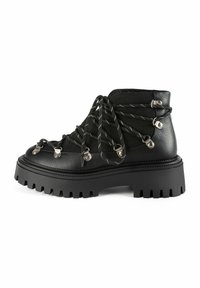 Botas de tobillo de cuero negro con punta redonda, suela pronunciada con relieve y herrajes plateados. Presentan cordones cruzados y una superficie texturizada.