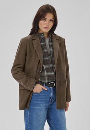 Brown suede blazer with a single button closure, notched lapels, and two front pockets, paired with a plaid shirt and blue jeans.