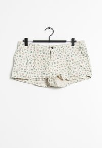 Shorts floreali con uno sfondo crema, decorati con piccoli fiori blu e rosa, dotati di chiusura frontale a bottone e due tasche laterali.