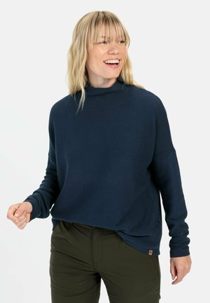 Marineblå, ribbet pullovertrøje med høj hals, lange ærmer og en afslappet pasform. Har et lille mærketag på kanten.