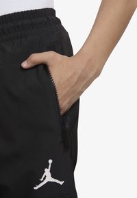 Czarne szorty z kieszenią na zamek i białym logo Jumpman. Wykonane z gładkiego materiału z elastycznym pasem, prezentujące dopasowany krój.