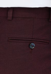 Bordowe spodnie z teksturowanej tkaniny, z przednią kieszenią zamykaną na czarny guzik oraz subtelnymi detalami przeszycia.
