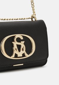 Svart läder crossbody-väska med en texturerad yta, utrustad med ett guldfärgat logoknäpp och kedjerem. Kompakt rektangulär form.