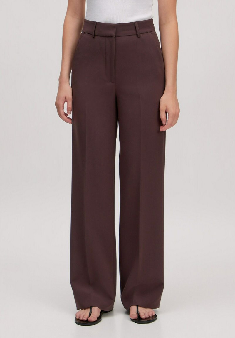Wijde benen broek in een diep bordeauxrood. Gemaakt van een gladde stof met een tailor fit, met een hoge taille en zijzakken.