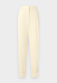 Pantaloni sartoriali color crema a vita alta con pieghe, gambe affusolate e risvoltini sulle caviglie, esposti su uno sfondo neutro.