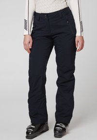 Marineblauwe skibroek met een gladde textuur, voorste drukknoopsluiting en ritszakken; gecombineerd met zwarte skibotten.