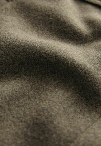 Textured wool fabric in olive green, featuring soft, undulating waves and a slightly fuzzy surface, with no visible patterns or accents.