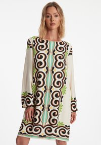 Langdurige jurk van lichtgewicht stof met een gedurfde abstracte print in zwart, groen en turquoise op een crèmekleurige achtergrond.