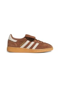 Hnedé tenisky Adidas Spezial s bielymi pruhmi, gumenou podrážkou a pásikom na suchý zips cez šnúrky, zobrazené z pravého bočného profilu.