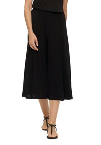Zwarte culotte-pantalons met plooien, gemaakt van een lichtgewicht stof, met een wijde pijpdesign. Draagt met platte, gespen sandalen.