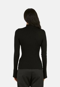 Maglione a collo alto nero a coste, aderente con maniche lunghe, tessuto strutturato. Il retro ha una finitura liscia e una scollatura bassa.