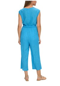 Jumpsuit blu, con texture, maniche corte, vita con cintura e vestibilità ampia. Il tessuto presenta un sottile motivo a righe.