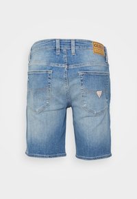 Pantalones cortos de mezclilla en azul claro con un aspecto desgastado, que presentan un parche de logo marrón, dos bolsillos traseros y detalles de costura en un color contrastante.