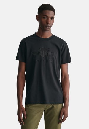 Zwarte katoenen t-shirt met een verhoogd logoontwerp op de borst, ronde halslijn en korte mouwen. Glad textuur met een normale pasvorm.