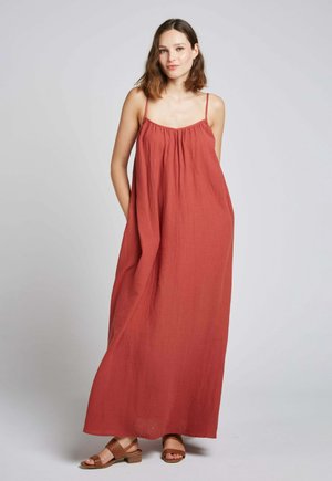 Robe maxi de couleur terracotta, fabriquée dans un tissu léger avec une coupe ample, dotée de fines bretelles et d'un décolleté froncé.