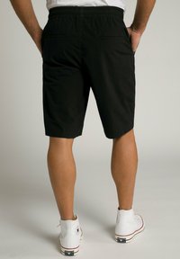 Sorte shorts med elastisk talje, to baglommer og lige snit. Bæret med hvide høje sneakers.