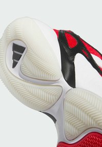 Suola di scarpa sportiva rossa e nera, con una suola in gomma bianca testurizzata dotata di un modello di trazione multidirezionale e tre linee nere di accento.