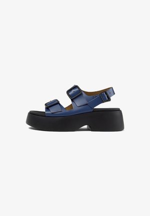 Sandalias con plataforma azul con tiras anchas, hebillas ajustables y una suela negra texturizada, con un diseño elegante y moderno.
