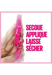 Produit rose vif tenu dans une main, conception de boîte rectangulaire avec des instructions textuelles. L'arrière-plan est flou, mettant l'accent sur le produit.