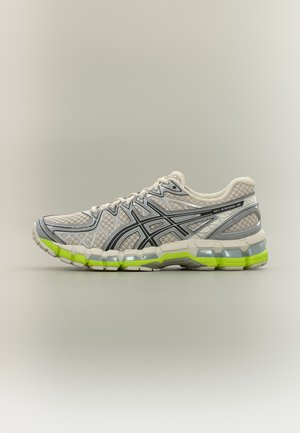 Chaussure de course gris clair et jaune néon avec détails noirs, tige en mesh, semelle rembourrée et design à lacets, vue de côté.