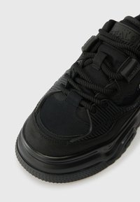 Mustad mustajad sinised tossud tekstuursed kangast ja kummist aktsentidega. Omavad pehmendatud keelt, paksu tallaga ning keerulist paelussüsteemi toe tagamiseks.