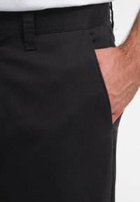 Pantalones ajustados negros de algodón suave, con bolsillos laterales y un diseño sutil y limpio. Costuras visibles a lo largo de la cinturilla.