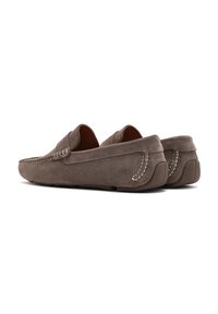 Mocasines de gamuza marrón con detalles de costura, tacón ligeramente elevado y suela de goma texturizada para mayor agarre. Diseño clásico sin cordones.
