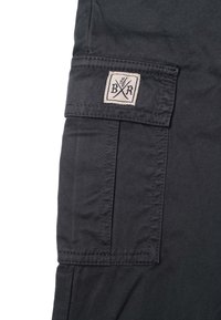 Svarta cargobyxor i tyg med en rektangulär ficka. Har en beige etikett med "BXR" och ett design av korsade yxor. Strukturerat material.