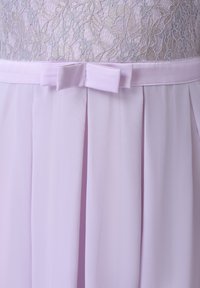 Robe lavande pâle avec corsage en dentelle, ceinture en satin et petit nœud décoratif à la taille au-dessus des panneaux plissés de la jupe.