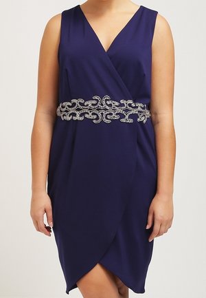 Abito blu navy senza maniche con scollo a V e cintura decorata in argento in vita, modello mostrato dalle spalle alle ginocchia.