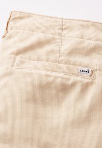 Bež kordura tkanina s prikazom stražnjeg džepa na kojem je ušiven Levi's logo etiketa.