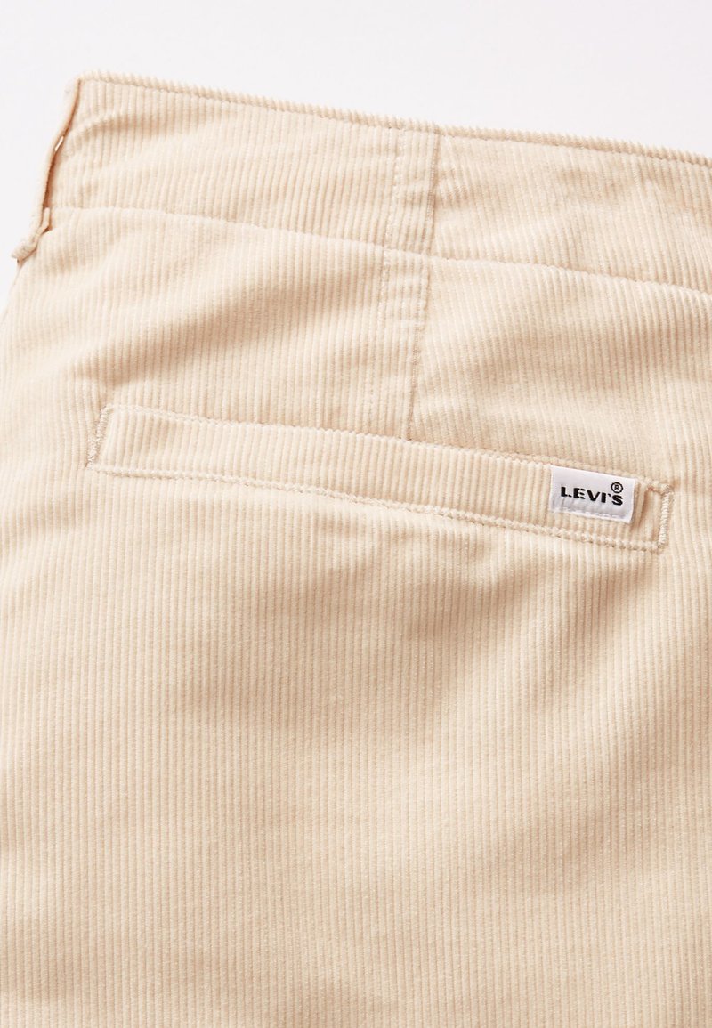Beiger Cordstoff mit einer hinteren Tasche, an der der Levi's Logo-Tag am Rand genäht ist.