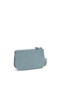 Lichtblauwe stoffen pouch met ritssluiting, voorzien van een zachte, nepleren pompon als accent, compacte rechthoekige vorm en subtiele stikdetails.