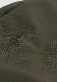 Detailní pohled na olivově zelenou látku s jemnou žebrovanou strukturou a měkkými záhyby.