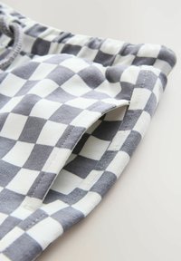 Tissu à carreaux gris et blanc avec une texture douce, doté d'une taille élastique et d'une ouverture de poche latérale.
