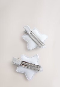 Weiße haiförmige Haarklammern mit silbernem Metallbeschlag, die eine strukturierte Stoffoberfläche und glänzende Akzente am Clip aufweisen.