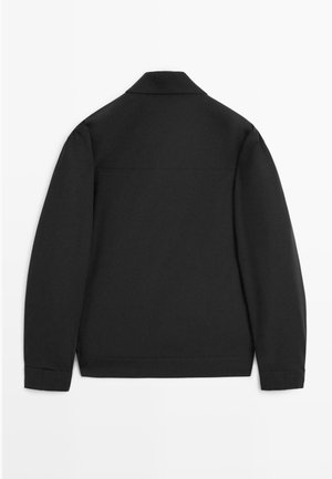 Veste noire à manches longues avec un col, un ourlet droit, et sans motifs ni embellissements visibles, vue de dos sur un fond blanc.