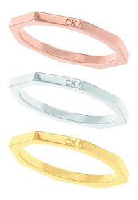 Conjunto de tres anillos geométricos en tonos de oro rosado, plata y oro. Cada uno presenta un acabado pulido con un sutil grabado de "CK".