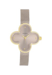 Montre avec bracelet en mailles argentées, dotée d'un cadran en forme de trèfle, d'un fond gris clair, d'accents dorés, de marqueurs horaires ronds et d'une couronne sur le côté pour les réglages.